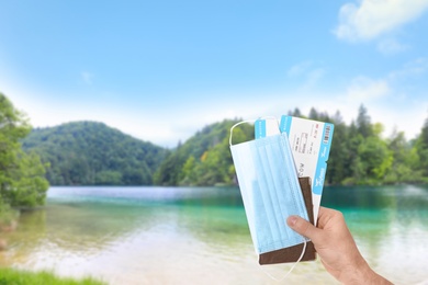 Image of Man holding passport, tickets and protective mask outdoors, closeup. Travel during quarantine