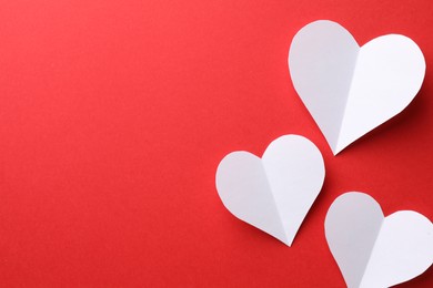 Photo of White paper hearts on red background, flat lay. Space for text