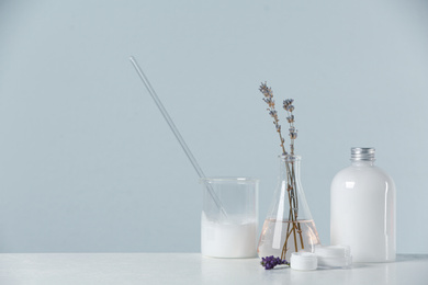 Photo of Herbal cosmetic products, laboratory glassware and ingredients on white table, space for text