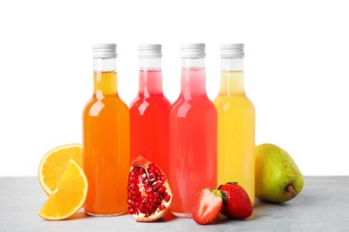 Photo of Delicious kombucha in glass bottles and fresh fruits on grey table against white background