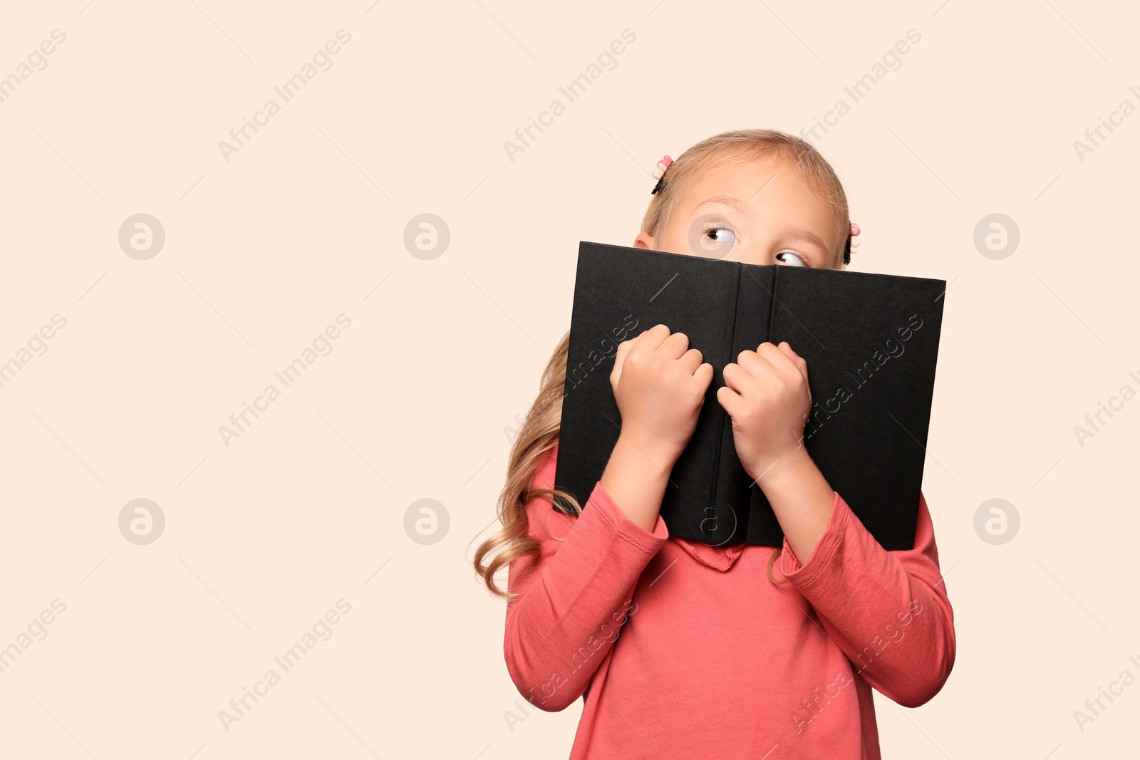 Photo of Little girl with book on light background. Space for text