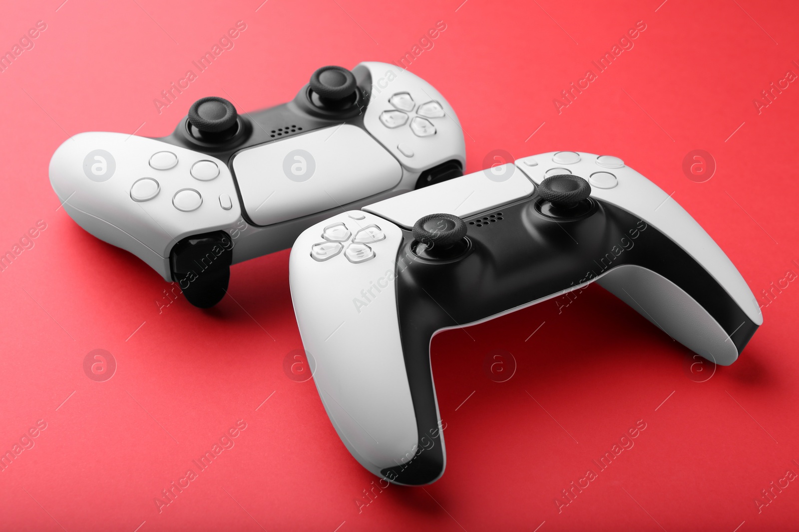 Photo of Two wireless game controllers on red background