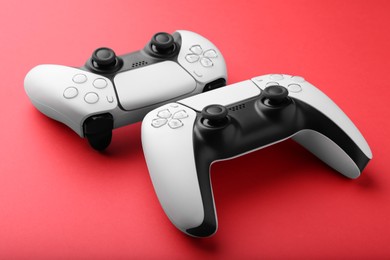 Photo of Two wireless game controllers on red background