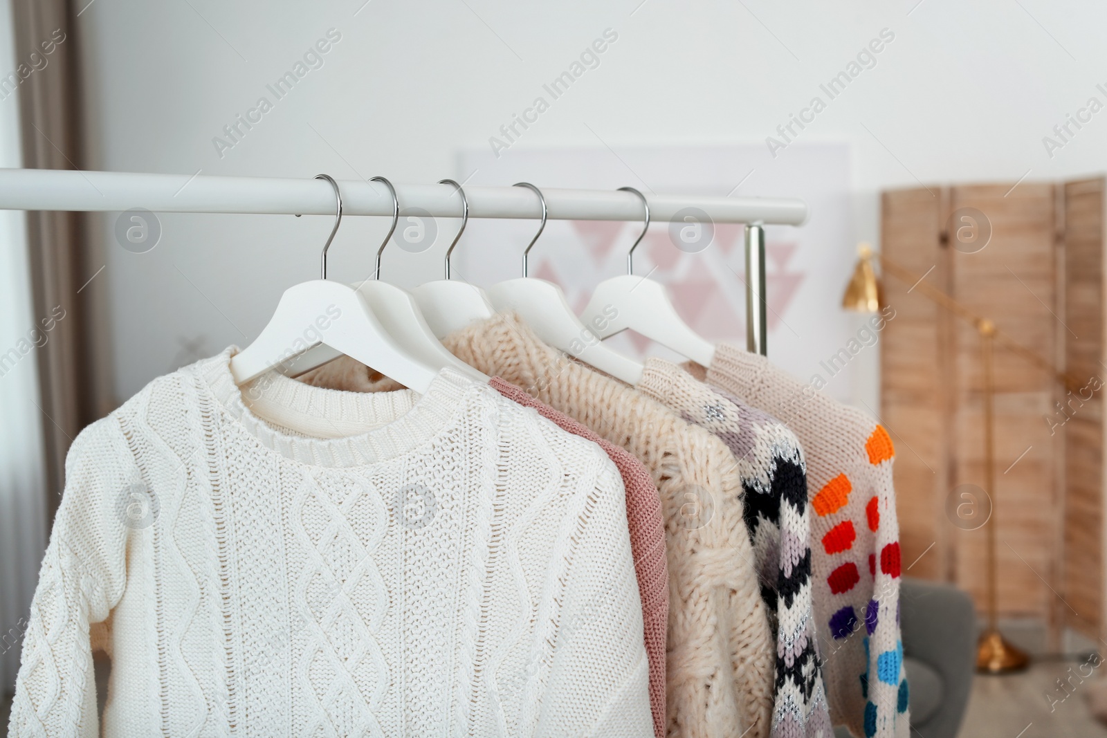 Photo of Wardrobe rack with warm clothes indoors, closeup