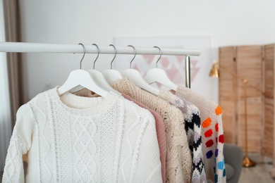 Photo of Wardrobe rack with warm clothes indoors, closeup
