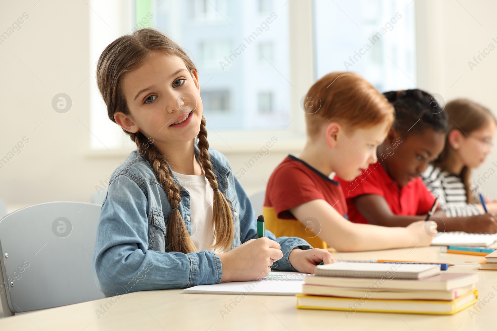 Photo of Smiling girl with her classmates studying in classroom at school