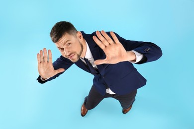 Man in suit evading something on light blue background, above view