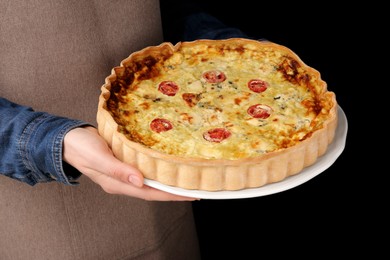 Photo of Woman with delicious homemade cheese quiche on black background, closeup