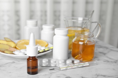 Nasal spray and different cold remedies on white marble table