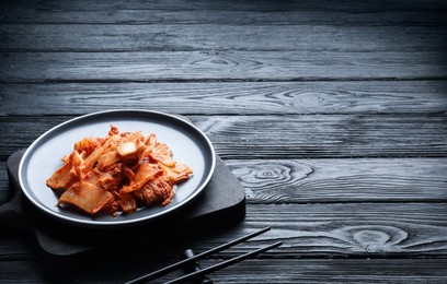 Photo of Delicious kimchi with Chinese cabbage served on black wooden table. Space for text