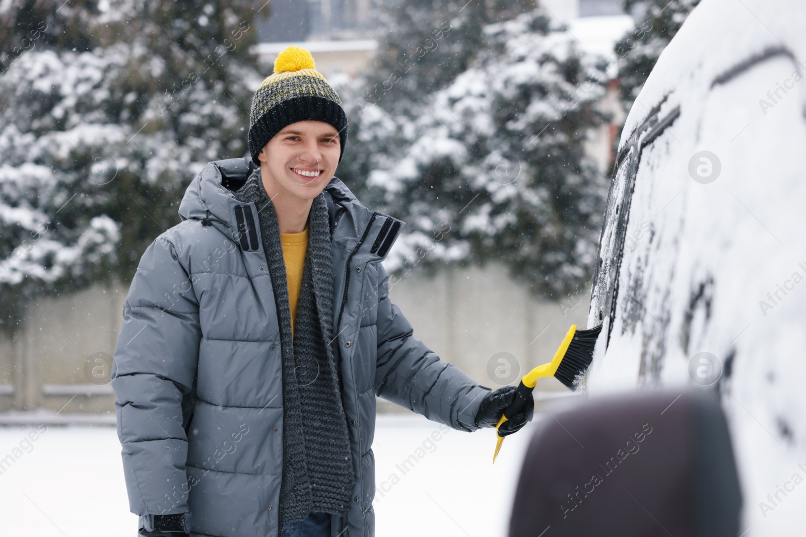 Photo of Man cleaning snow from car window outdoors