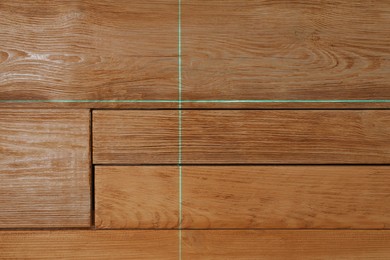 Photo of Cross lines of laser level on wooden wall