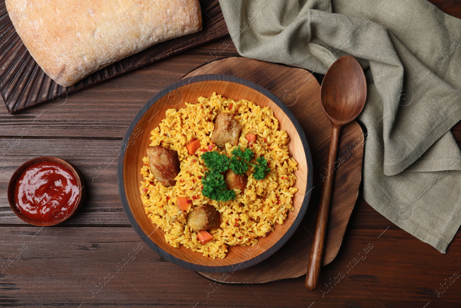 Photo of Flat lay composition with rice pilaf and meat on wooden background, top view