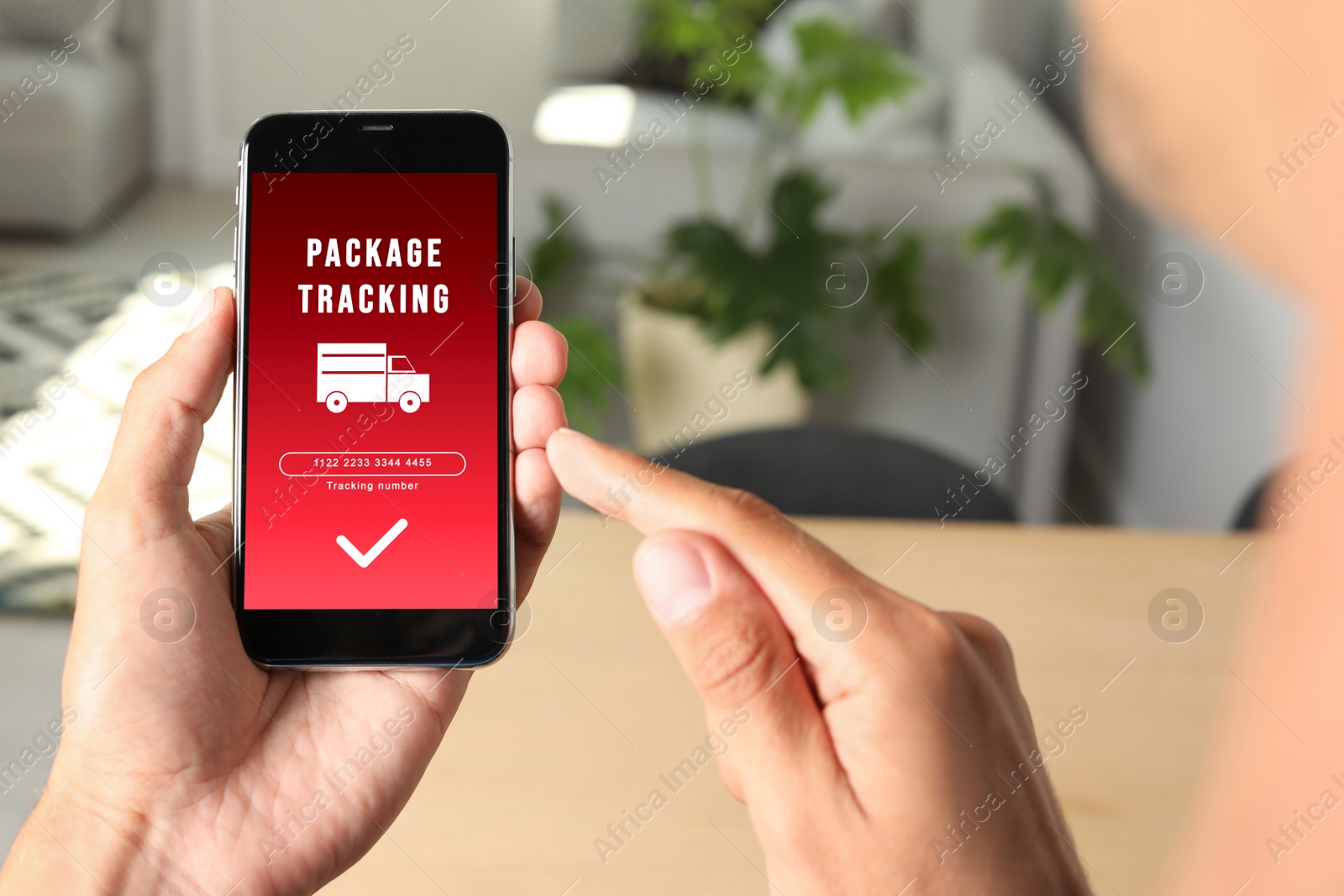 Image of Man tracking parcel via smartphone indoors, closeup