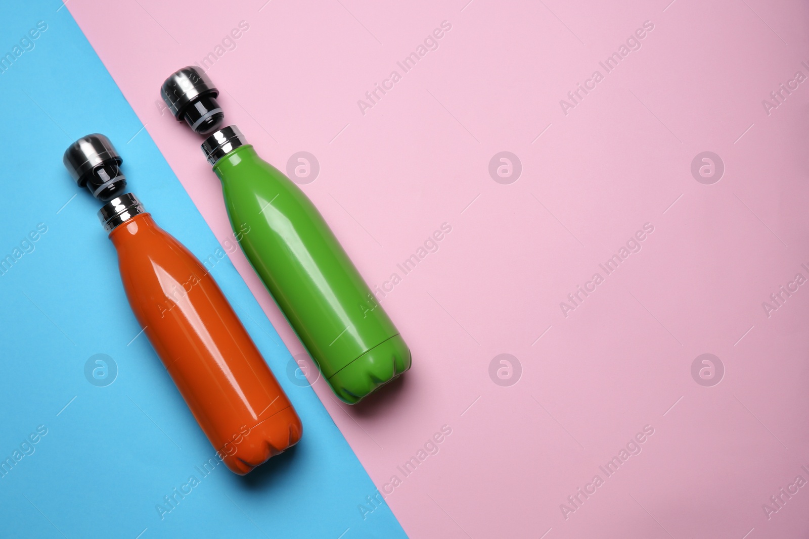 Photo of Modern thermo bottles on color background, flat lay. Space for text