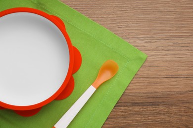 Plastic bowl and spoon on wooden background, top view with space for text. Serving baby food