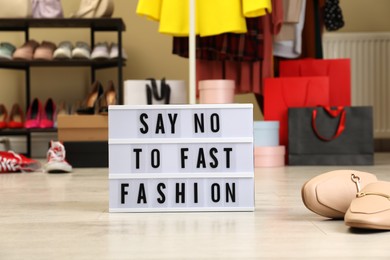 Photo of Lightbox with phrase SAY NO TO FAST FASHION on floor indoors