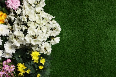 Photo of Different beautiful flowers on green grass, flat lay. Space for text