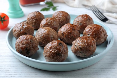Photo of Tasty cooked meatballs served on white wooden table, closeup