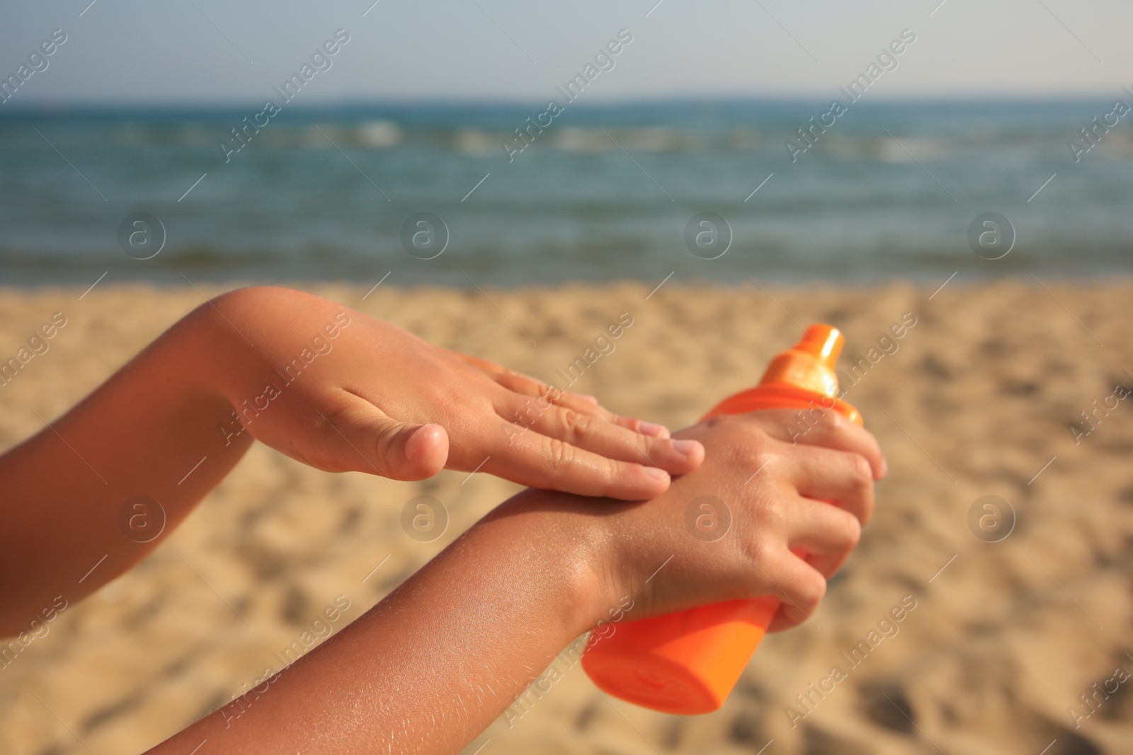 Photo of Child applying sunscreen near sea, closeup. Sun protection care