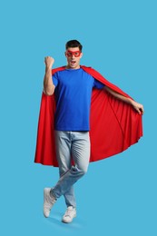 Photo of Man wearing superhero cape and mask on light blue background