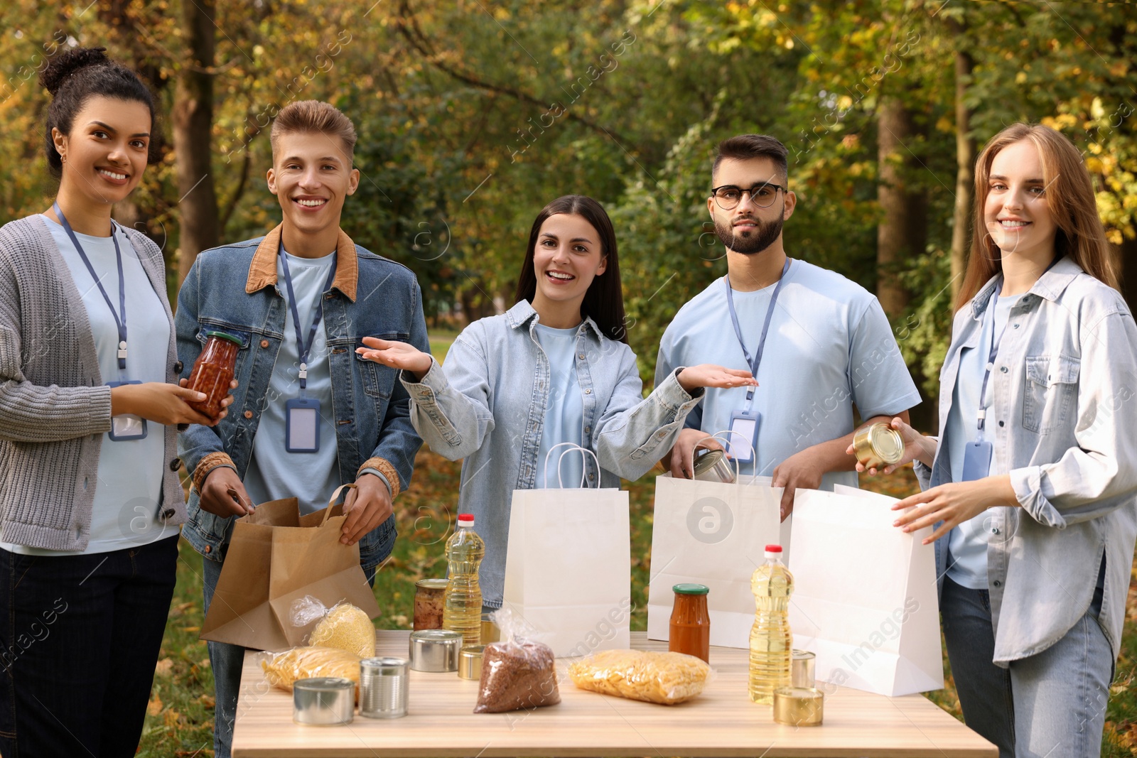 Photo of Portrait of volunteers packing food products at table in park