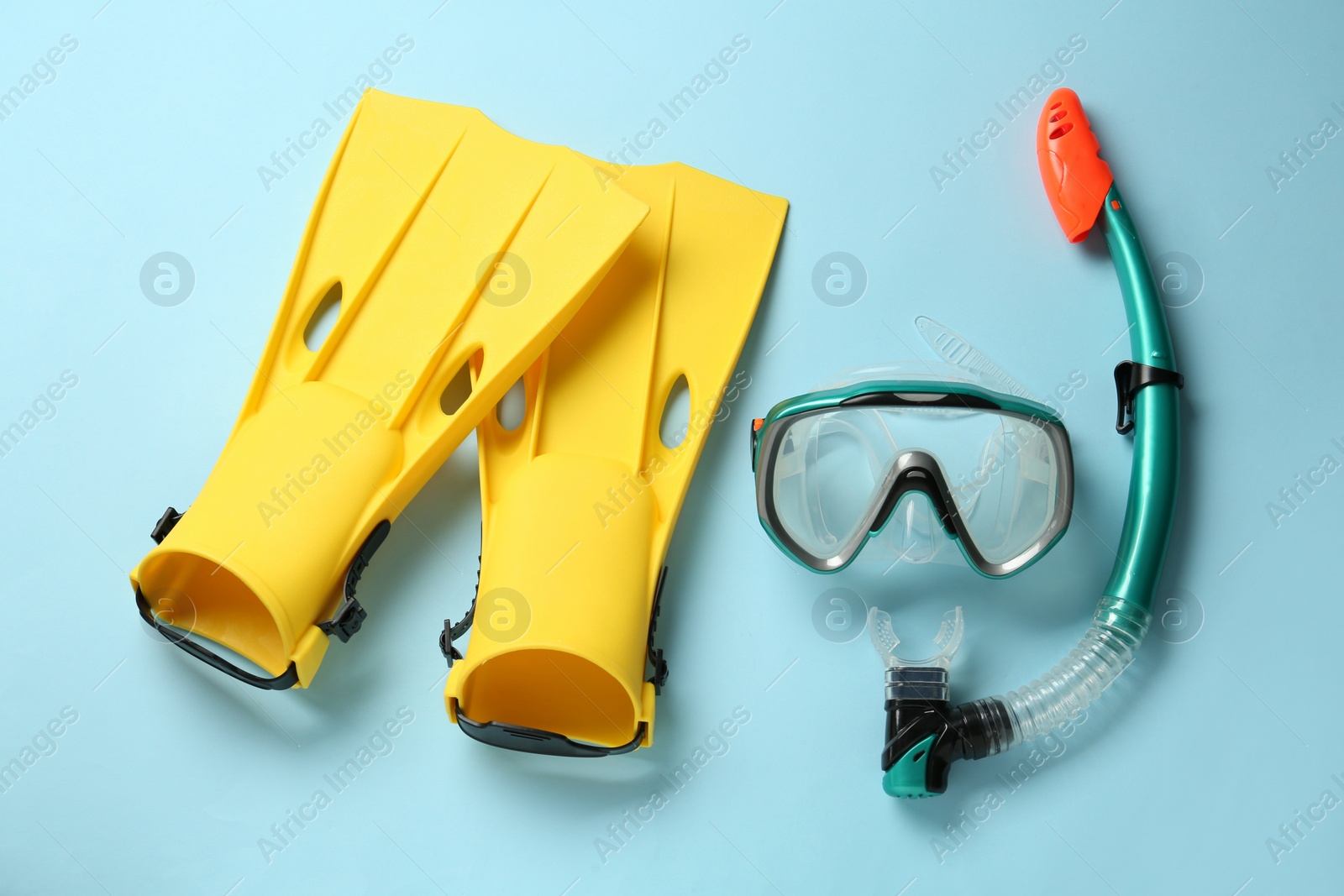 Photo of Pair of yellow flippers and mask on light blue background, flat lay