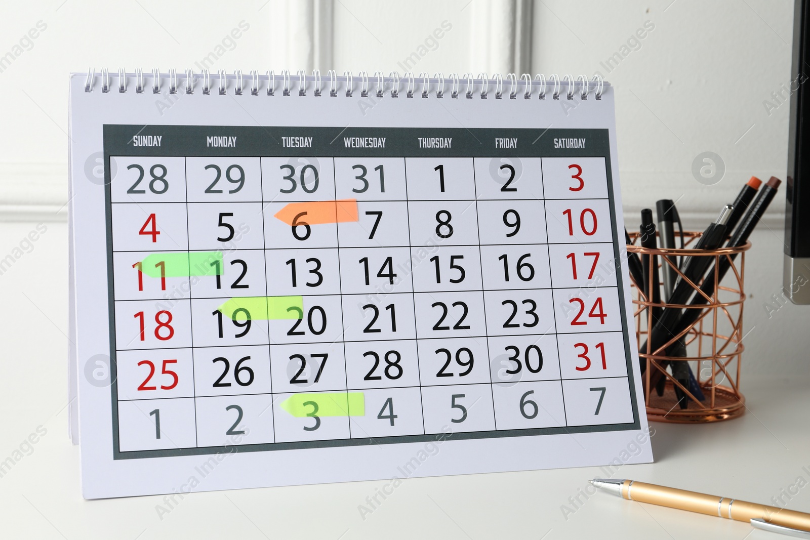 Photo of Timetable. Calendar with marked dates and stationery on white table indoors