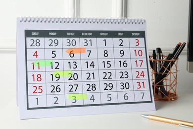 Timetable. Calendar with marked dates and stationery on white table indoors