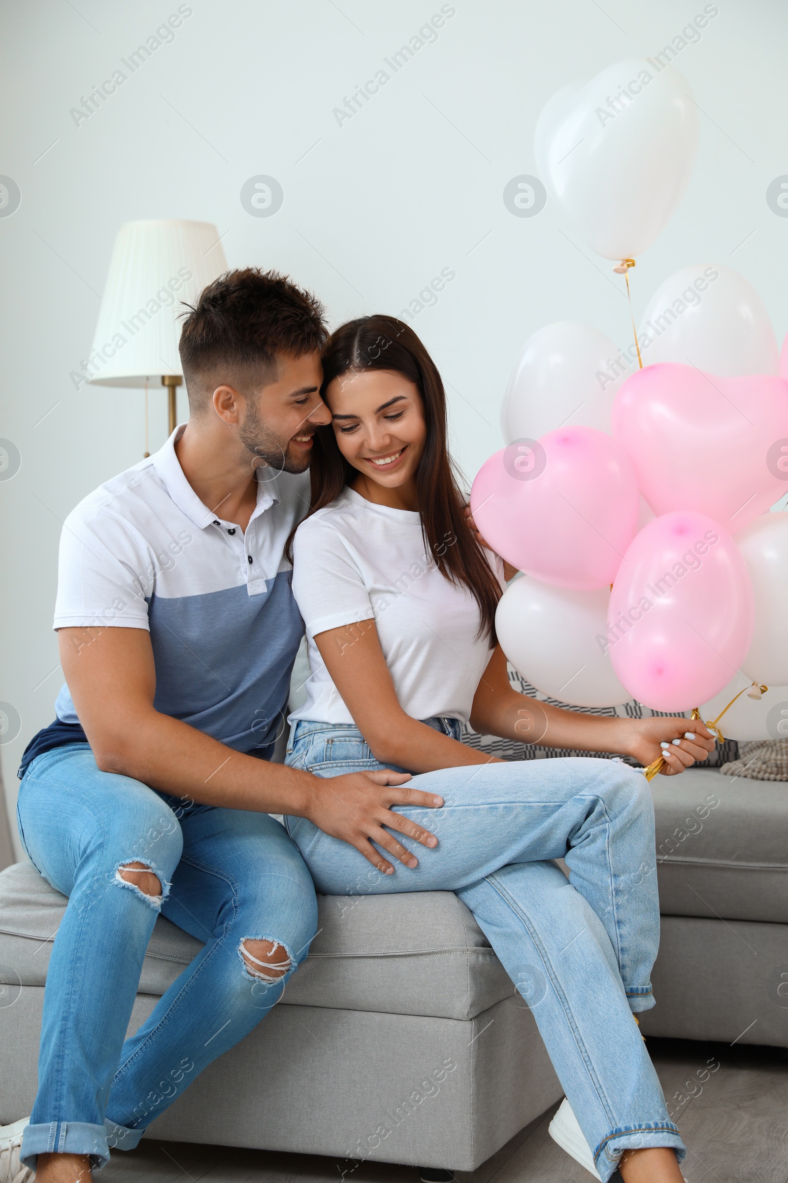 Photo of Young couple with air balloons at home. Celebration of Saint Valentine's Day