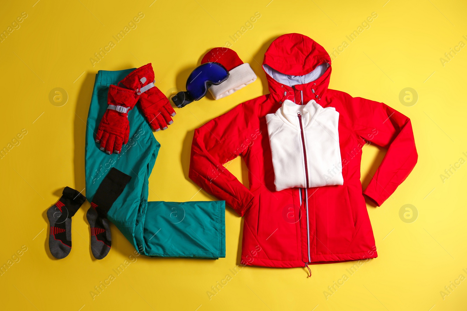 Photo of Stylish winter sport clothes on yellow background, flat lay