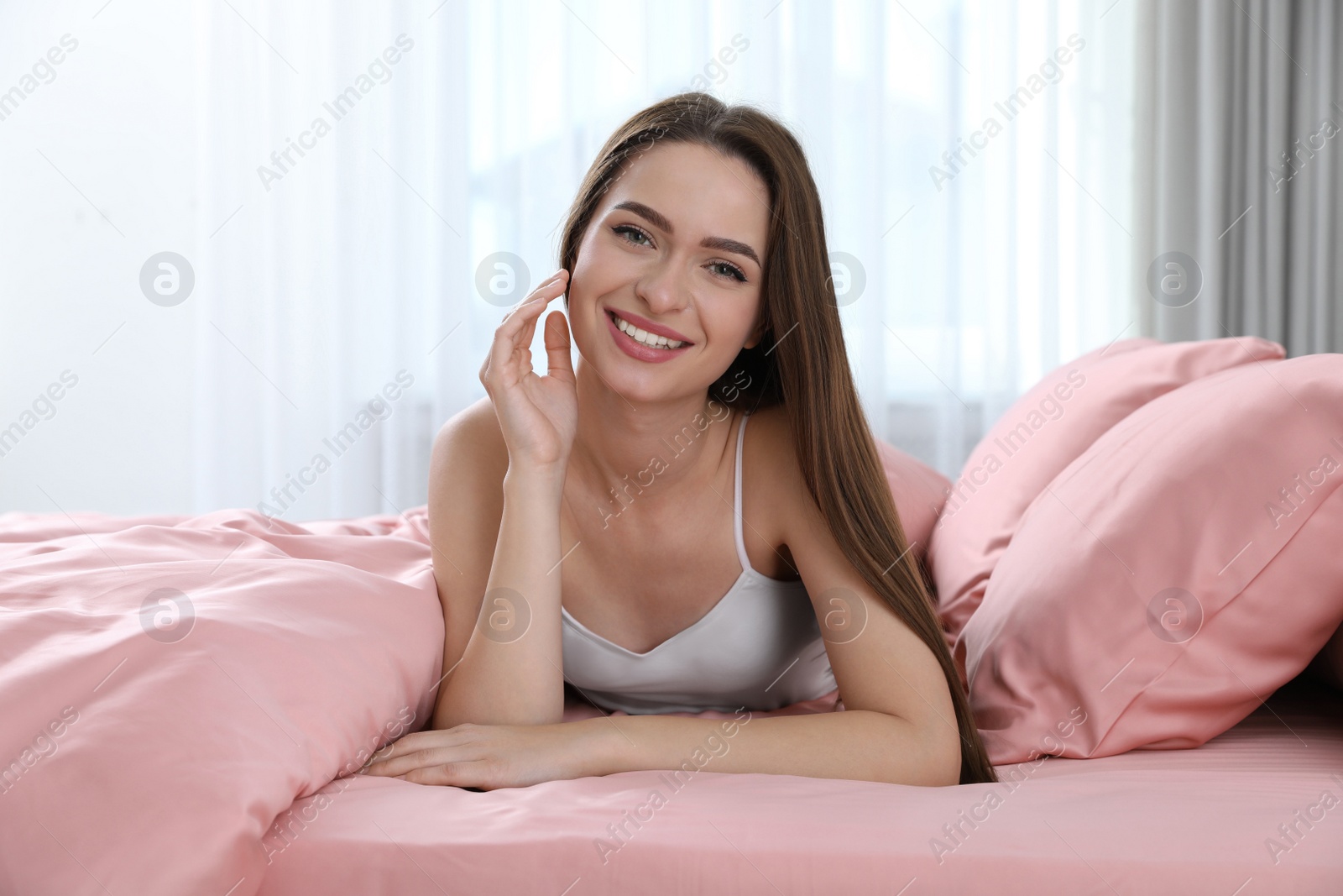 Photo of Young woman lying on comfortable bed with silky linens