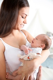 Photo of Young woman with her newborn baby on blurred background