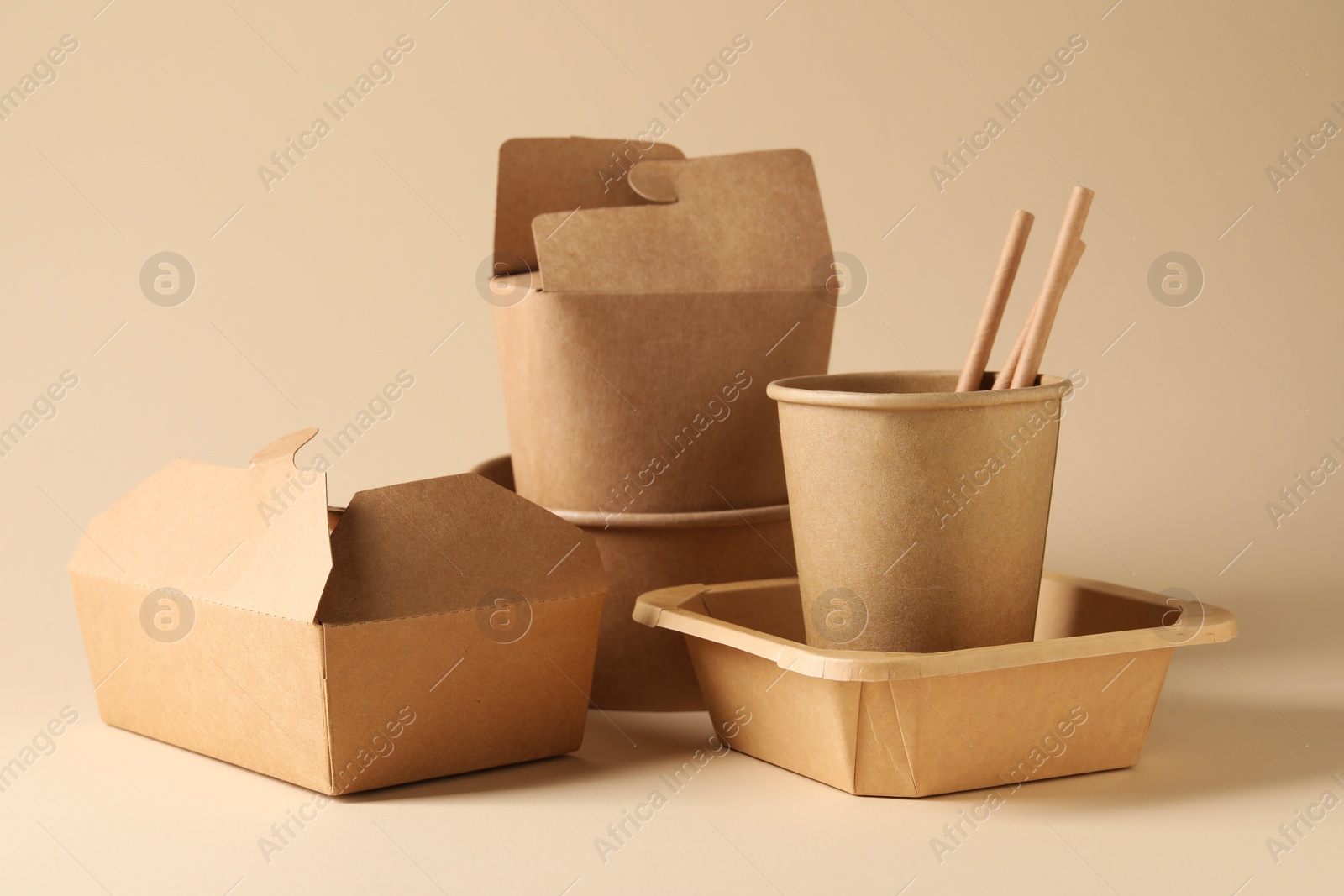 Photo of Eco friendly food packaging. Paper containers and tableware on beige background