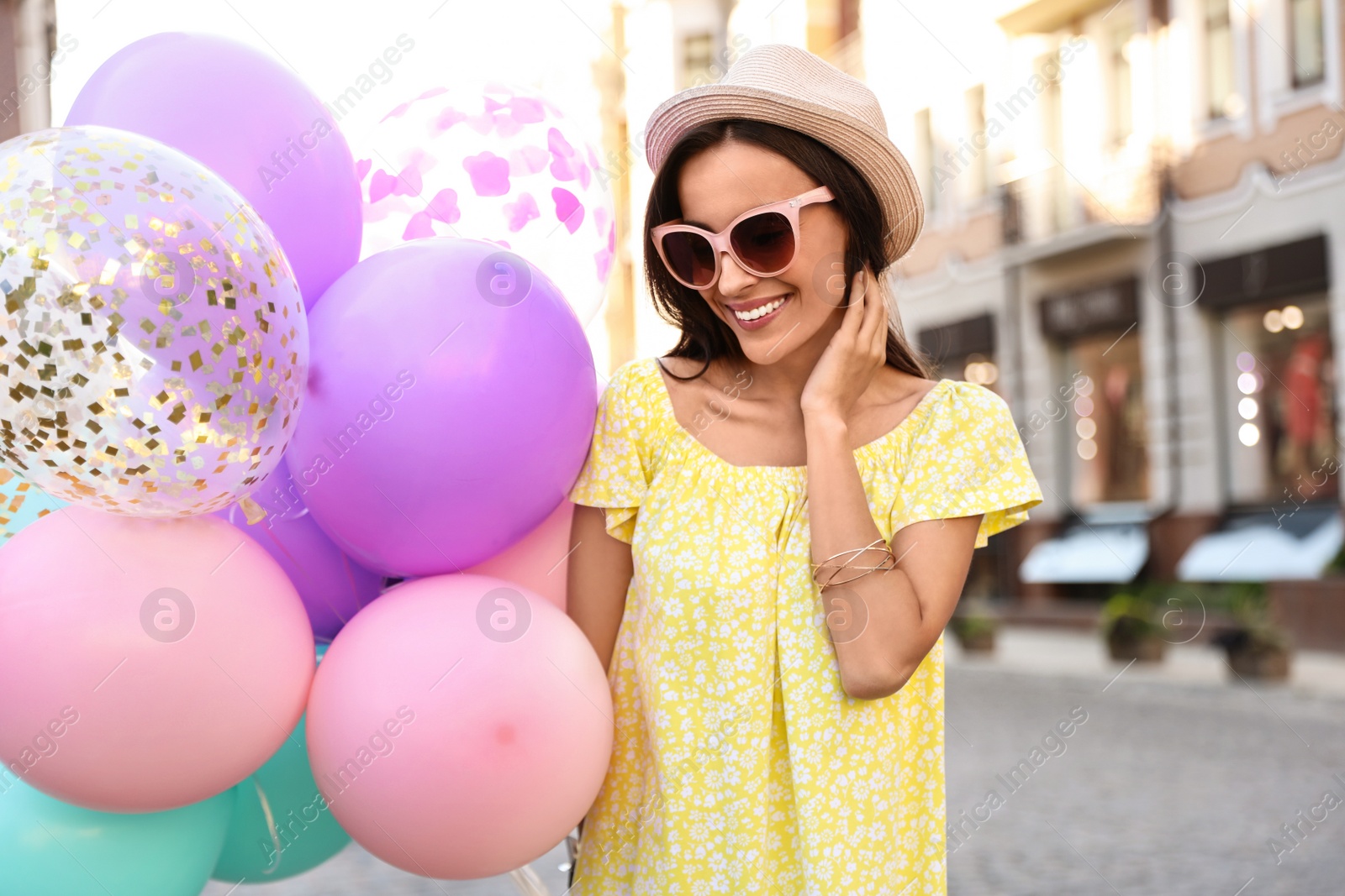 Photo of Beautiful young woman with color balloons on city street