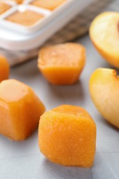 Photo of Frozen nectarine puree cubes and ingredient on light grey table, closeup