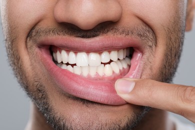 Man showing healthy gums on grey background, closeup