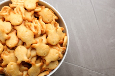 Delicious goldfish crackers in bowl on grey table, top view