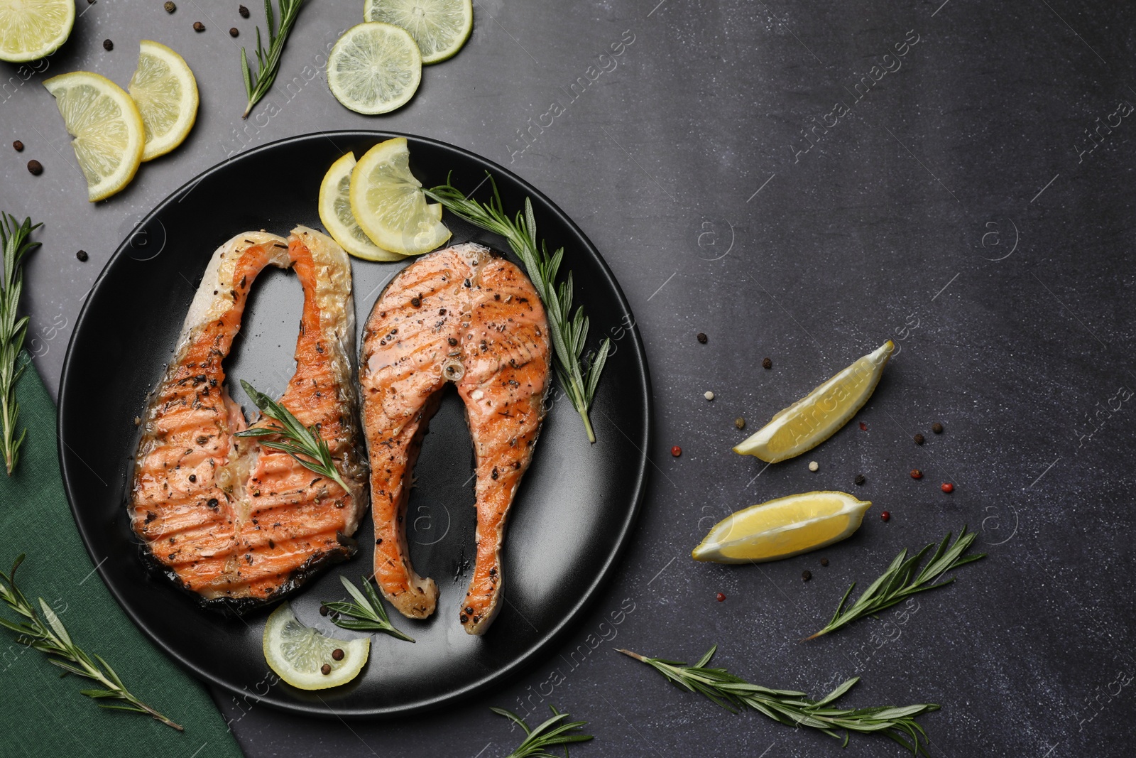 Photo of Plate with tasty salmon steaks on black table, flat lay. Space for text