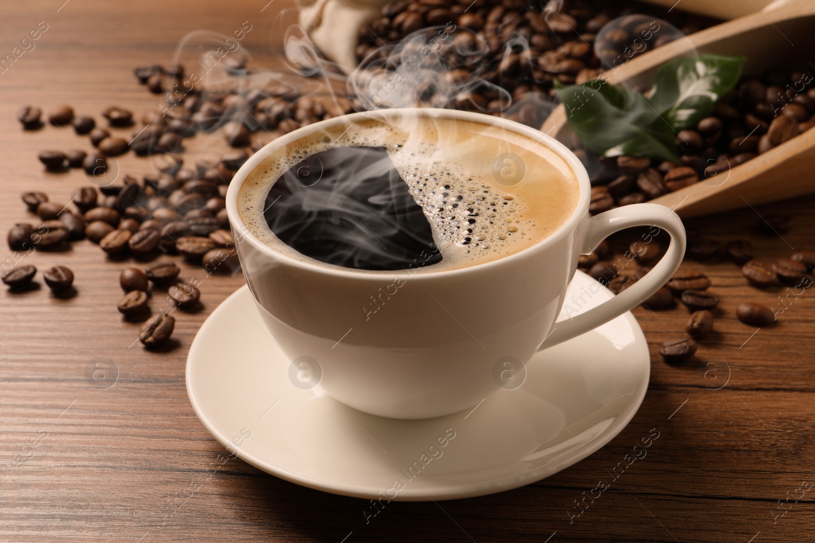 Image of Cup of aromatic hot coffee and beans on wooden table, closeup