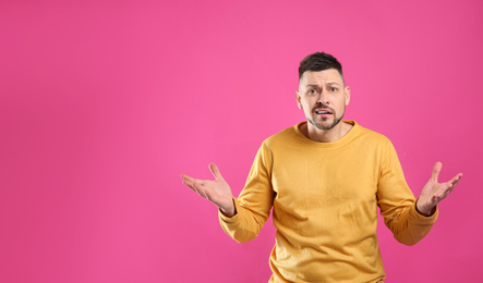 Emotional man on pink background, space for text