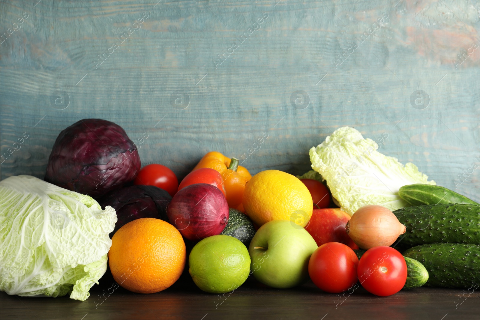 Photo of Fresh vegetables and fruits on table against wooden background, space for text