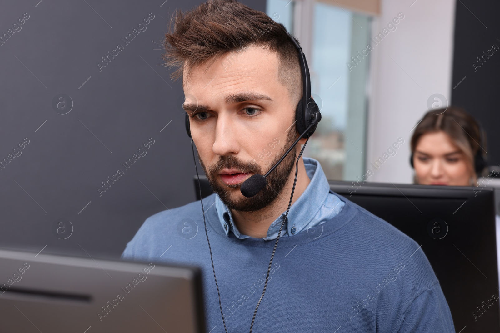 Photo of Handsome call center operator with headset working in modern office
