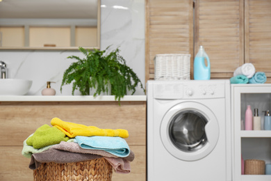 Wicker basket with laundry in bathroom. Space for text