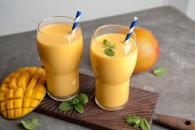 Photo of Glasses of fresh mango drink and fruits on table