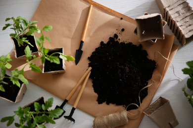 Photo of Flat lay composition with tomato seedlings, gardening tools and soil on white wooden table