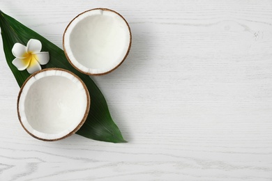 Flat lay composition with halves of coconut on white wooden background. Space for text