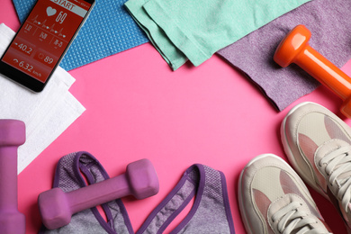 Frame made with fitness equipment and smartphone on pink background, flat lay. Space for text