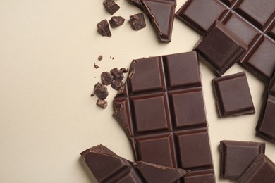 Pieces of delicious chocolate bars on beige background, flat lay