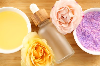 Purple sea salt, beautiful flowers and different spa products on wooden table, flat lay